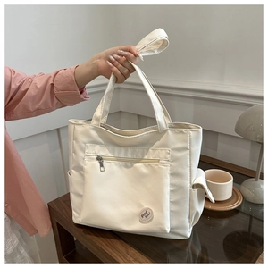 Detail of white multi-pocket canvas tote bag with front zipper and Good Luck emblem