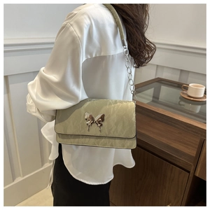 Detail of pistachio green pleated underarm bag with silver butterfly buckle and chain strap