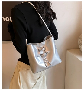 Detail of silver metallic ballet-style bucket bag with lace-up bow and thin shoulder strap