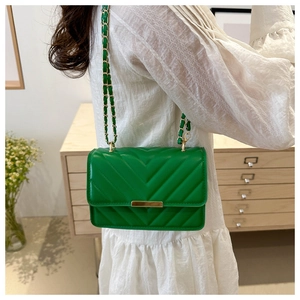 Detail der grünen V-gesteppten kleinen Tasche mit goldenem Kettenriemen am weißen Kleid