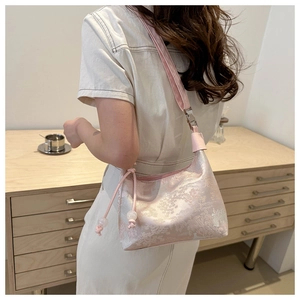 Détail du sac sous le bras en jacquard rose avec motifs floraux et breloques perles