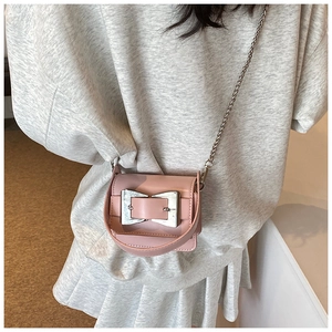 Detailed view of pink mini crossbody bag with silver bow clasp and chain strap on a model