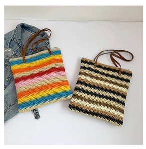 Dettaglio di borse tote intrecciate a righe colorate con manici in finta pelle marrone