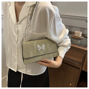 Detailed view of sage green pleated texture shoulder bag with silver butterfly buckle