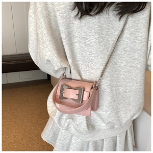 Close-up of pink mini crossbody bag with large silver buckle and metal chain strap