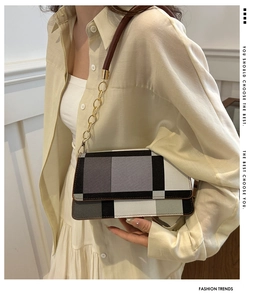 Detail of checkered crossbody bag with gold chain strap shown on model's shoulder