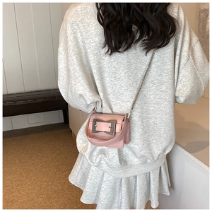 Detailed view of mini pink leather flap bag with silver buckle worn over grey hoodie