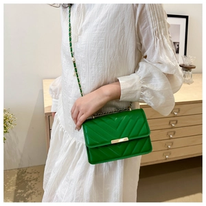 Detail der grünen Crossbody-Tasche mit V-Steppung, Goldverschluss und Perlen-Kette