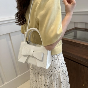 Elegant white crossbody bag with oversized bow detail and rounded top handle for women