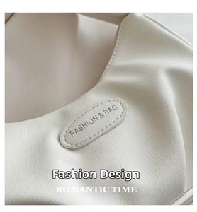 Close-up of cream white crescent bag showing cross-grain Saffiano texture and stitching