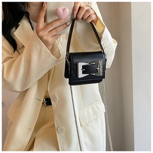 Close-up of black leather crossbody bag featuring a silver bow-shaped metal lock