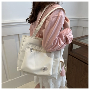 Detail of white ivory tote bag with cloud patch and zipper pocket on model