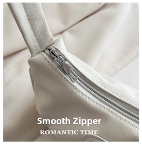 Detail of silver metal zipper on white leather crescent bag with Romantic Time text
