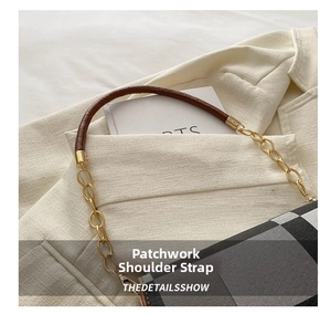 Detail of plaid shoulder bag showing leather strap and golden chain on beige texture