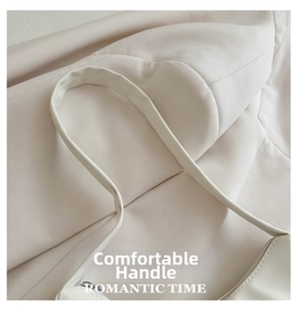 Detail view of the wide beige leather strap on a minimalist pleated shoulder bag