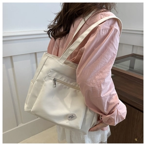 Close-up of cream canvas tote bag featuring side pockets and a 'good luck' circular patch