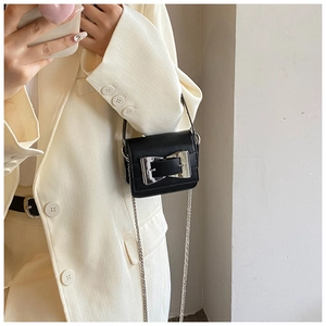 Close-up of a black matte leather mini crossbody bag with a large silver buckle detail