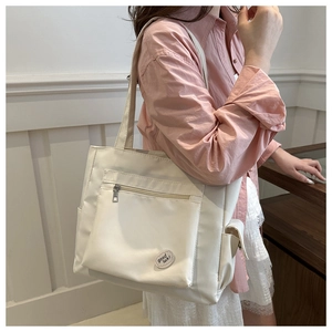 Detail of white nylon tote bag with side pocket and good luck round patch