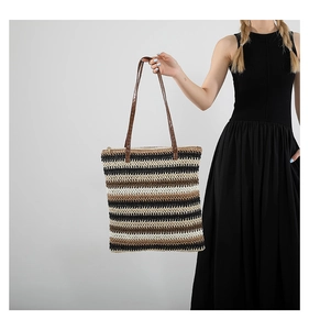 Detail of striped woven tote bag featuring synthetic leather handles and zipper closure