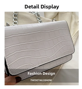 Close-up of white croc-embossed crossbody bag with silver thick metal chain detail