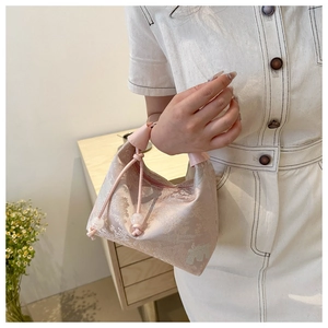 Détail d'un sac à main en satin rose avec motifs jacquard et cordon de serrage perlé