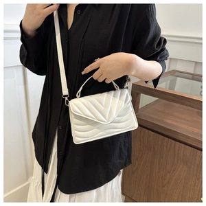 Detail of white quilted handbag with V-shaped stitching and gold-tone hardware