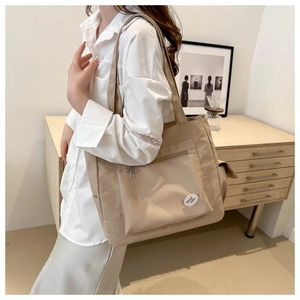 Asian model showing a large beige nylon tote bag with 'good luck' patch for daily commute