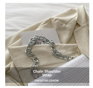 Close-up of white crocodile pattern shoulder bag with a bold silver metal chain strap