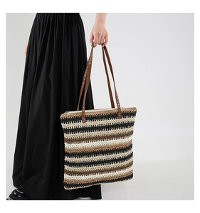 Detail of multi-color woven tote bag with leather straps and top zipper closure