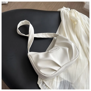 Detail of white pleated PU leather handbag featuring an embossed oval fashion label