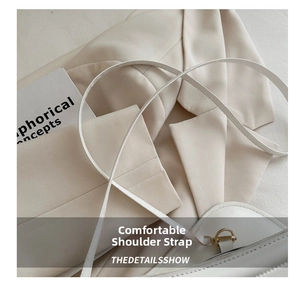 Close-up of cream leather shoulder bag strap with elegant gold ring hardware details