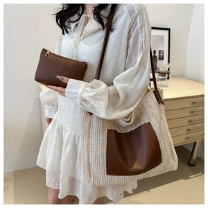 Detail view of woven straw tote bag set with brown leather pocket on a model