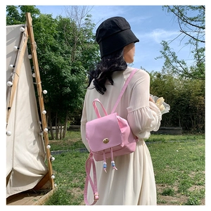 Detail view of a pink mini backpack with beaded drawstring and metal turn-lock on a model