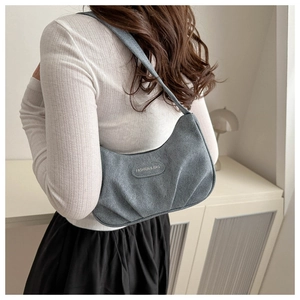 Detail view of grey pleated hobo bag featuring a central fashion logo patch and shoulder strap