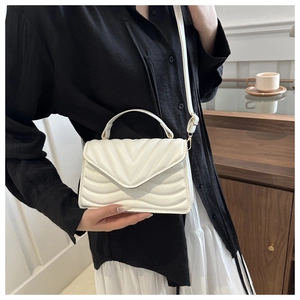 White wave quilted small square bag with chain strap and V-flap shown in lifestyle setting
