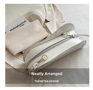 Detailed shot of white half-moon leather handbag with golden D-ring hardware