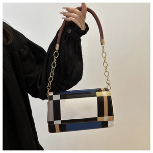 Detail of color-block flap bag with gold chain strap and textured leather finish