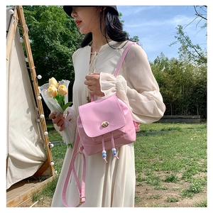 Pink glossy leather drawstring backpack with gold twist lock and beaded cord details