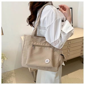 Beige nylon tote bag with functional pockets and decorative patch for daily commuting