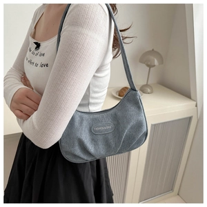 Blue canvas hobo bag featuring a crescent shape and a fashion logo plate on the front