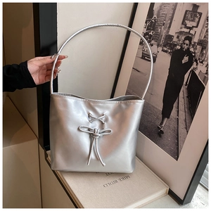 Close-up of silver shoulder bag featuring decorative lace-up bow and metallic finish