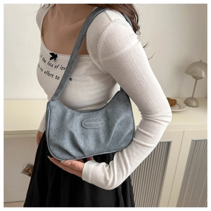 Detail of grey-blue ruched denim hobo bag with a fashion logo tag on the pleated surface