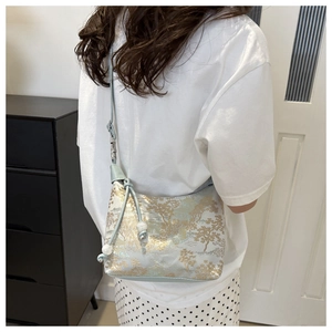 Détail du sac bandoulière en satin bleu clair avec broderies dorées et perles