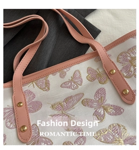 Close-up of pink butterfly embroidery on off-white tote bag with gold rivet details