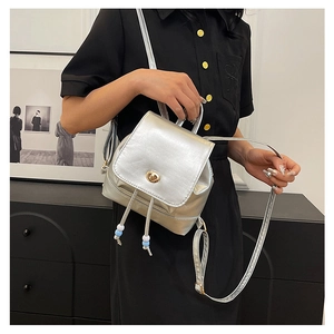 Detail of silver mini backpack featuring metallic texture and golden twist lock closure
