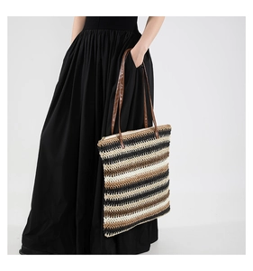 Detail of large woven tote bag with three-color stripes and brown leather straps
