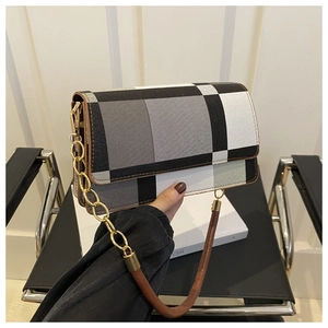 Close-up of contrast checkered handbag with golden chain detail and brown leather handle
