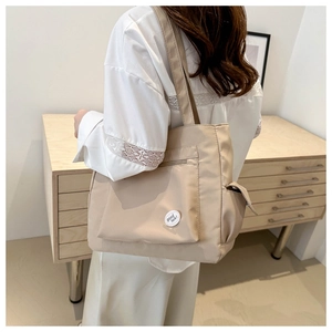 Detail of beige nylon tote bag with functional zipper pocket and good luck patch