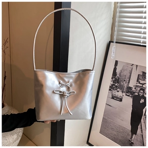 Close-up of silver bucket bag with metallic luster, cross laces and bow decoration