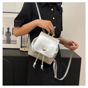 Close-up of a mini silver metallic backpack with drawstring detail and metal twist lock